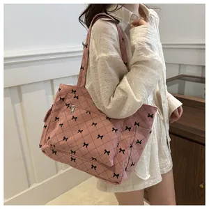 Macro view of pink corduroy tote bag with black bow patterns and quilted stitching details