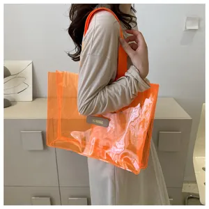 Detail view of transparent orange tote bag with wide strap and side leather brand label