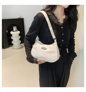 Detail of white nylon half-moon shoulder bag with SHILAIEN logo worn by model