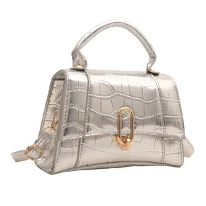 Detail of silver crocodile-textured square bag with golden rotary lock and top handle