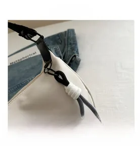 Détail de la boucle en métal noir et du nœud de serrage bicolore sur le sac en nylon blanc