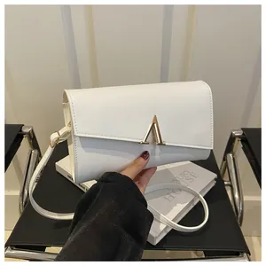 Gros plan d'un sac enveloppe en cuir blanc avec un fermoir en métal doré en forme d'A