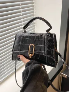 Detail of black crocodile pattern leather bag with elegant golden U-shaped metal buckle lock