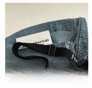 Détail du tissu denim bleu clair avec coutures renforcées et bandoulière réglable