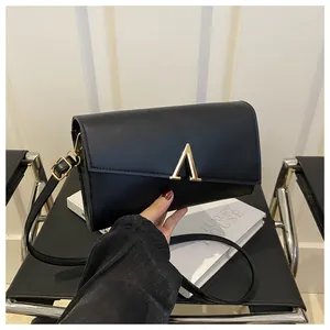 Détail du sac bandoulière en similicuir noir avec boucle dorée en A et bandoulière