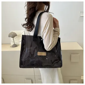Detailed side view of a large black semi-transparent PVC tote bag with comfortable fabric strap