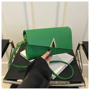 Détail d'un sac bandoulière vert lime en similicuir avec boucle métallique en V doré