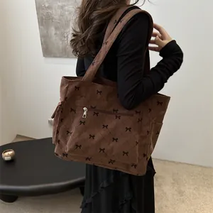 Brown corduroy tote bag with bow print and vintage quilted design in a side view