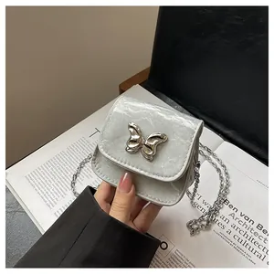 Detail of silver mini chain bag featuring textured crinkled leather and butterfly metal buckle