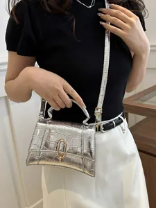 Detail of silver crocodile-embossed mini bag with golden buckle on a shoulder strap