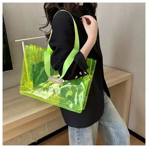 Neon green transparent PVC tote bag with wide fabric strap shown on model's shoulder