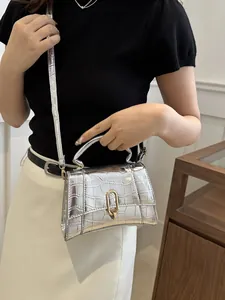 Detail showing the silver crocodile embossed texture and golden U-lock on the small handbag