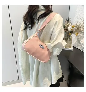 Detailed side view of pink nylon shoulder bag with white piping and logo on model
