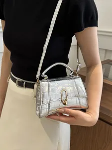 Detail of silver crocodile pattern handbag with golden U-shaped lock and smooth handle