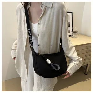 Détail d'un sac bandoulière noir en nylon avec une large sangle marquée du mot Fashion