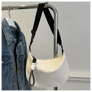 Détail du sac bandoulière demi-lune blanc en toile avec sangle noire et nœud décoratif