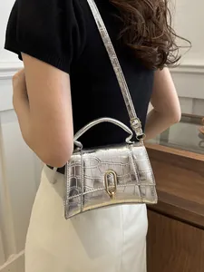 Silver crocodile pattern handbag shown on a model with gold metal clasp detail