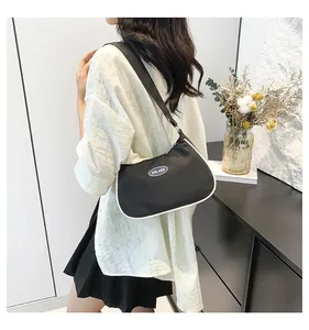 Detailed view of black crescent shoulder bag with white trim and branded blue logo patch