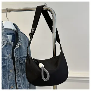 Détail du sac croissant noir avec bandoulière lettrée et tirettes en corde tressée