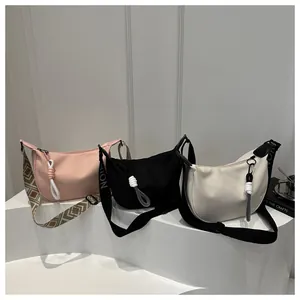 Trois sacs bandoulière en nylon croissant en rose, noir et beige avec larges sangles