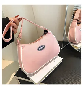 Detail of pink nylon crescent bag with white piping and round logo on a mirror
