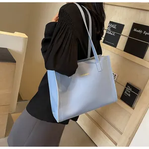 Sac fourre-tout en cuir bleu clair avec surpiqûres blanches et logo doré sur mannequin