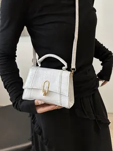 Detail of white crocodile embossed leather handbag with gold oval clasp and round handle