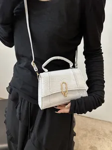 Detail of white crocodile embossed leather handbag featuring elegant gold U-shaped hardware