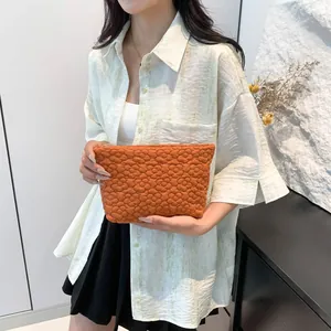 Orange quilted clutch bag with floral texture and lightweight fabric for women
