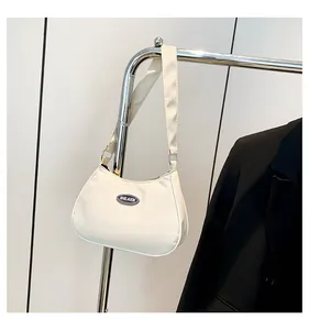 Detail view of cream nylon hobo bag featuring a black logo patch and durable metal buckle