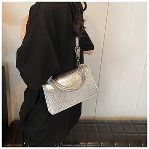 Detail of silver crocodile pattern handbag with adjustable strap shown on model