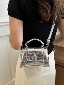 Detail of silver crocodile pattern mini crossbody bag shown on a model against white wall