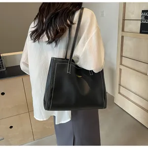 Détail du grand sac cabas noir avec surpiqûres blanches contrastées et logo doré brillant