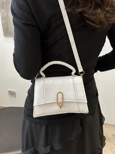 White faux leather crossbody bag with crocodile pattern worn by a model in black outfit