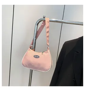 Detailed shot of a pink crescent shoulder bag with white trim and silver brand logo