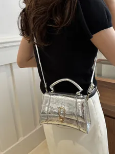 Silver crocodile embossed crossbody bag shown on model with gold hardware detail