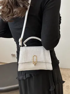 Detail of white crocodile pattern leather handbag with gold oval clasp and shoulder strap