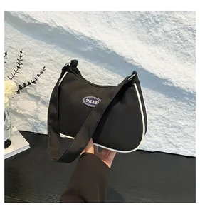 Detail of black nylon crescent shoulder bag with white piping and blue SHILAIE logo