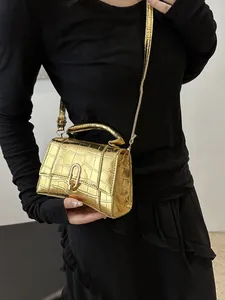 Detail of gold crocodile embossed mini handbag with metallic finish and adjustable strap