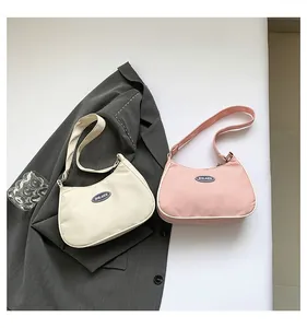 Flat lay of cream and pink nylon half-moon shoulder bags with minimalist logo detail