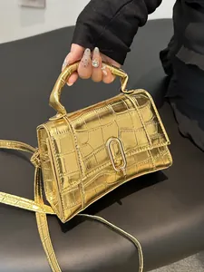 Detail of golden mirror finish crossbody bag with crocodile pattern and metal lock