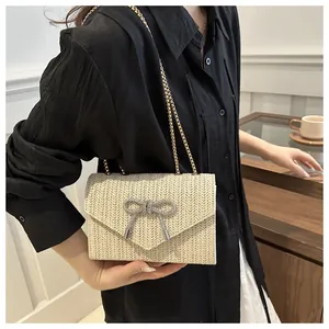 Détail du sac de plage tressé avec boucle papillon en strass et chaîne dorée chic