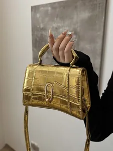 Detailed view of metallic gold crocodile embossed handbag with arched metal clasp