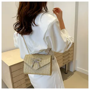 Détail du sac en paille tressée avec boucle papillon en cristal et bandoulière chaîne