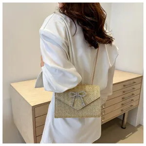 Détail du sac bandoulière en paille tressée avec papillon en strass et chaîne métallique