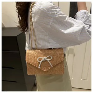 Vue détaillée du sac à bandoulière en paille avec boucle papillon en strass étincelants