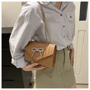 Vue détaillée d'un sac à rabat en paille tissée avec papillon en strass et chaîne dorée