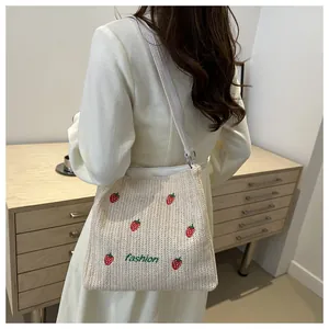 Détail de broderie fraise sur sac cabas en paille tissée avec texte fashion