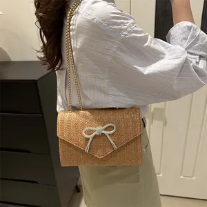 Sac bandoulière en paille tressée avec boucle papillon en strass et chaîne dorée