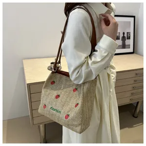 Détail de la broderie fraise et du lettrage fashion sur le sac cabas tressé beige clair